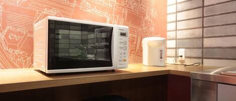 A kitchen with a microwave, a kettle, and a sink.