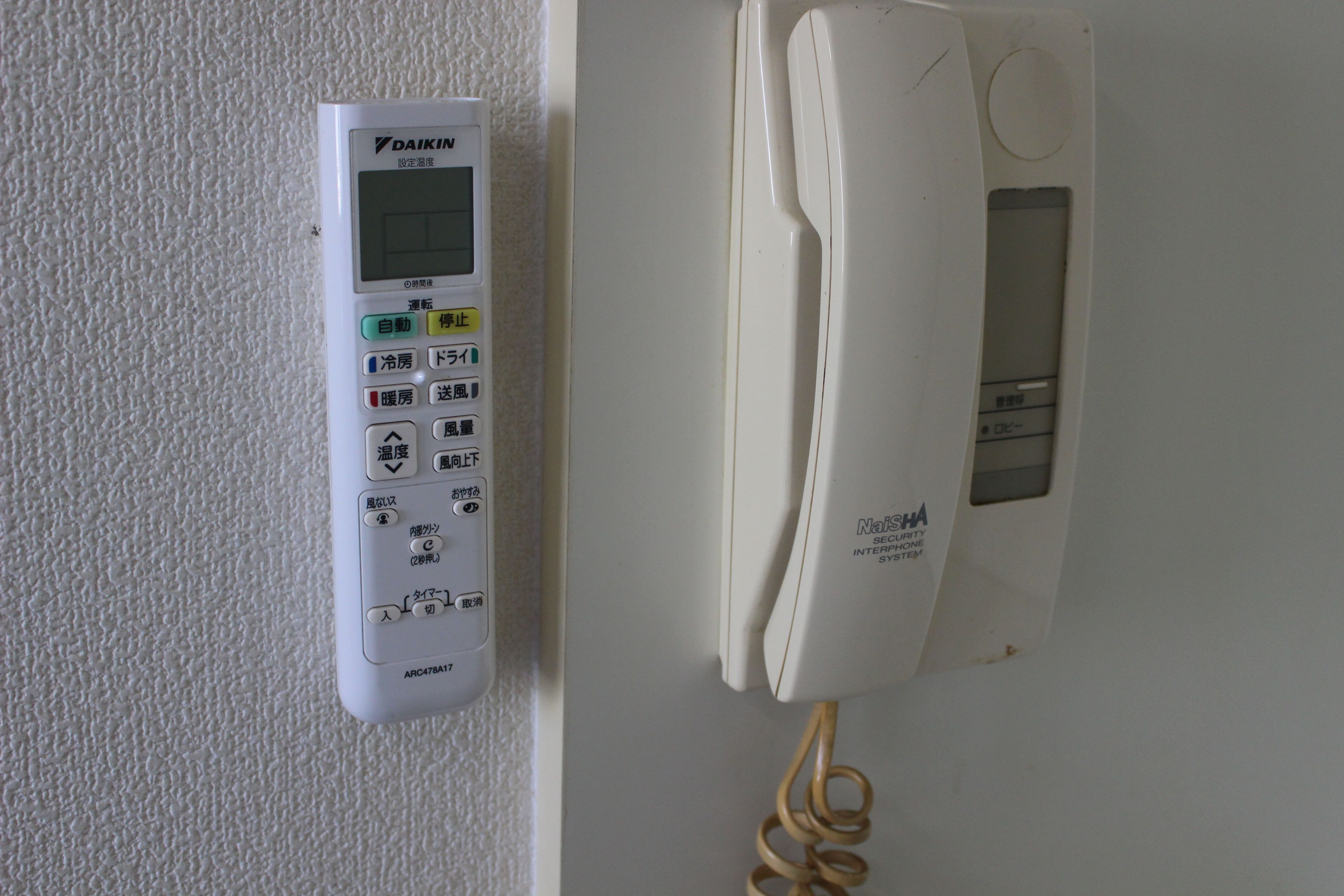 A wall-mounted telephone and a control panel with various buttons and a screen.