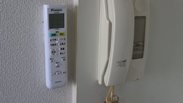 A wall-mounted telephone and a control panel with various buttons and a screen.