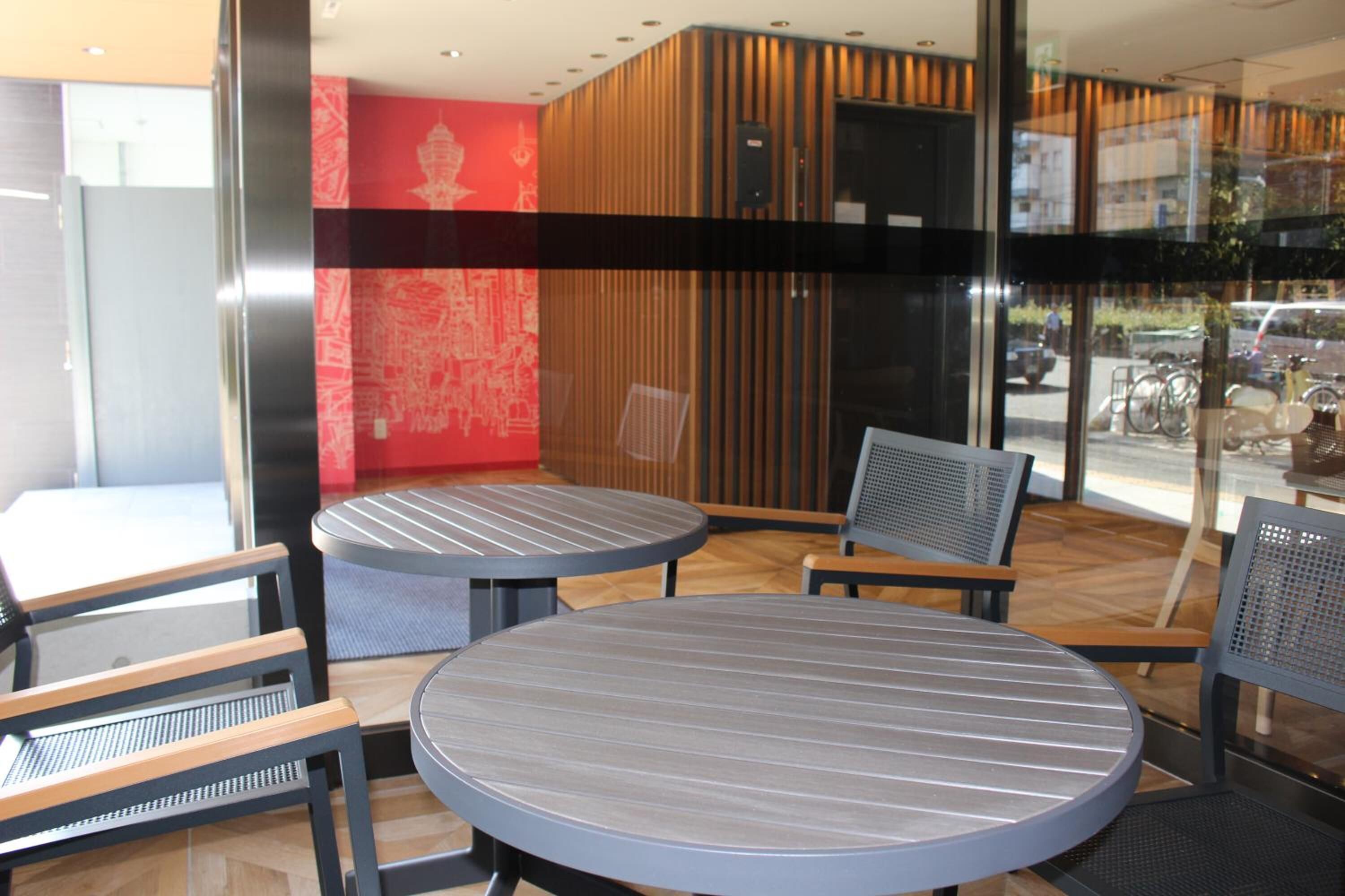 A modern indoor seating area with round tables and chairs, a wooden accent wall, and a view of the street through large windows.