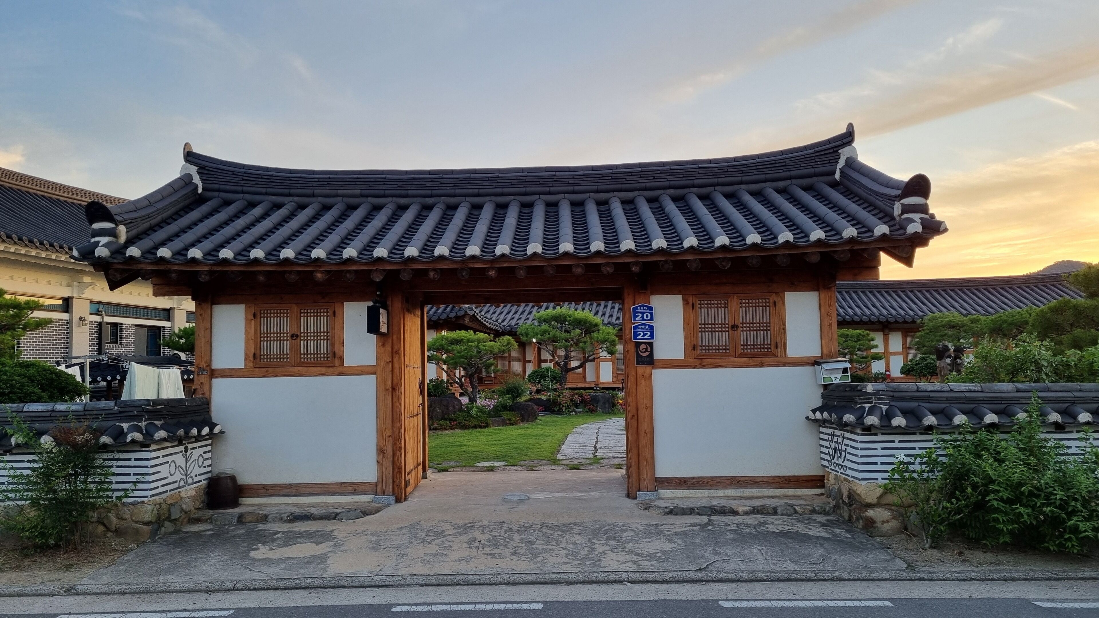 A traditional Korean gate with a curved roof, wooden pillars, and a stone pathway leading through.