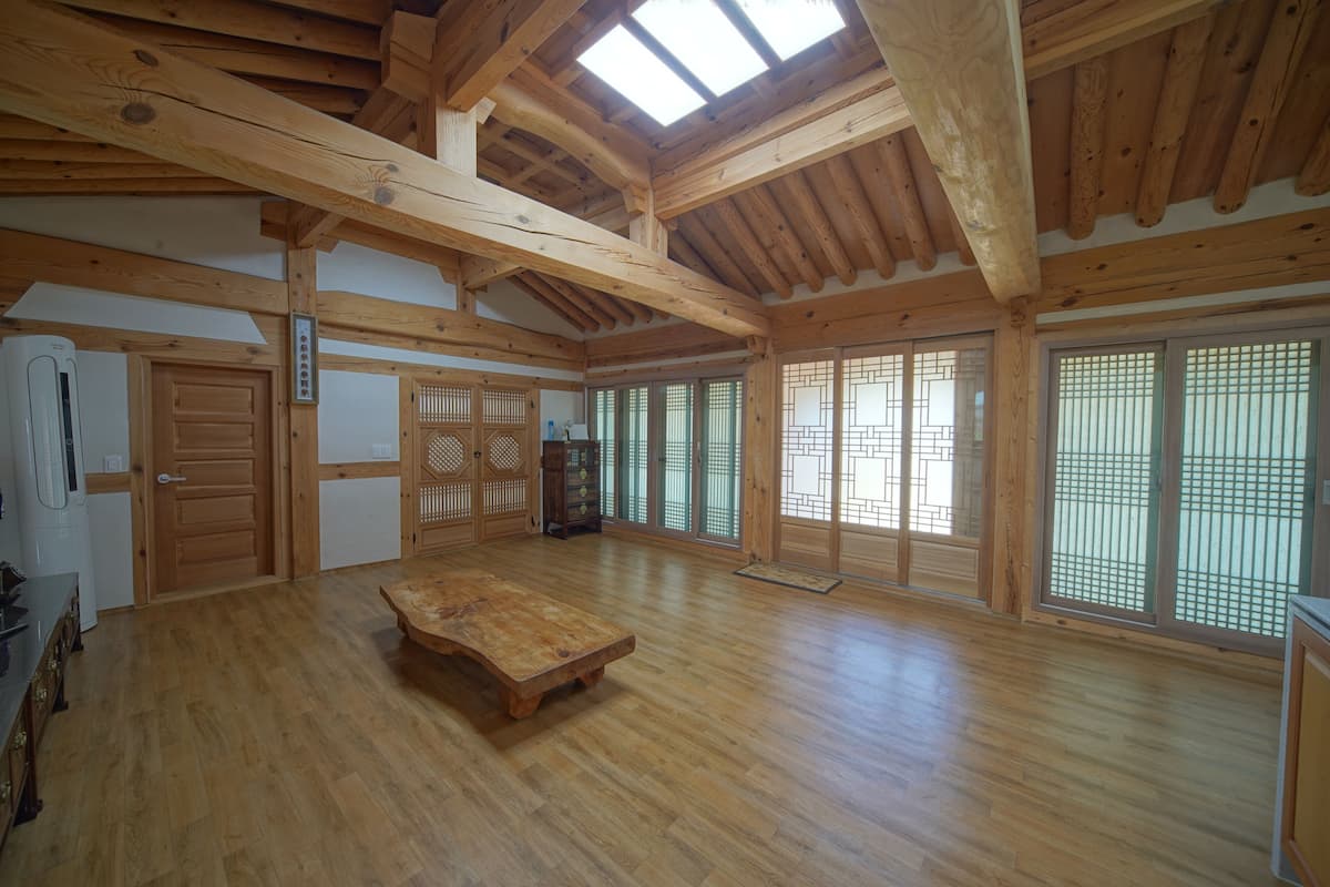 A spacious room with wooden floors, a large table, sliding doors with traditional lattice patterns, and a skylight.