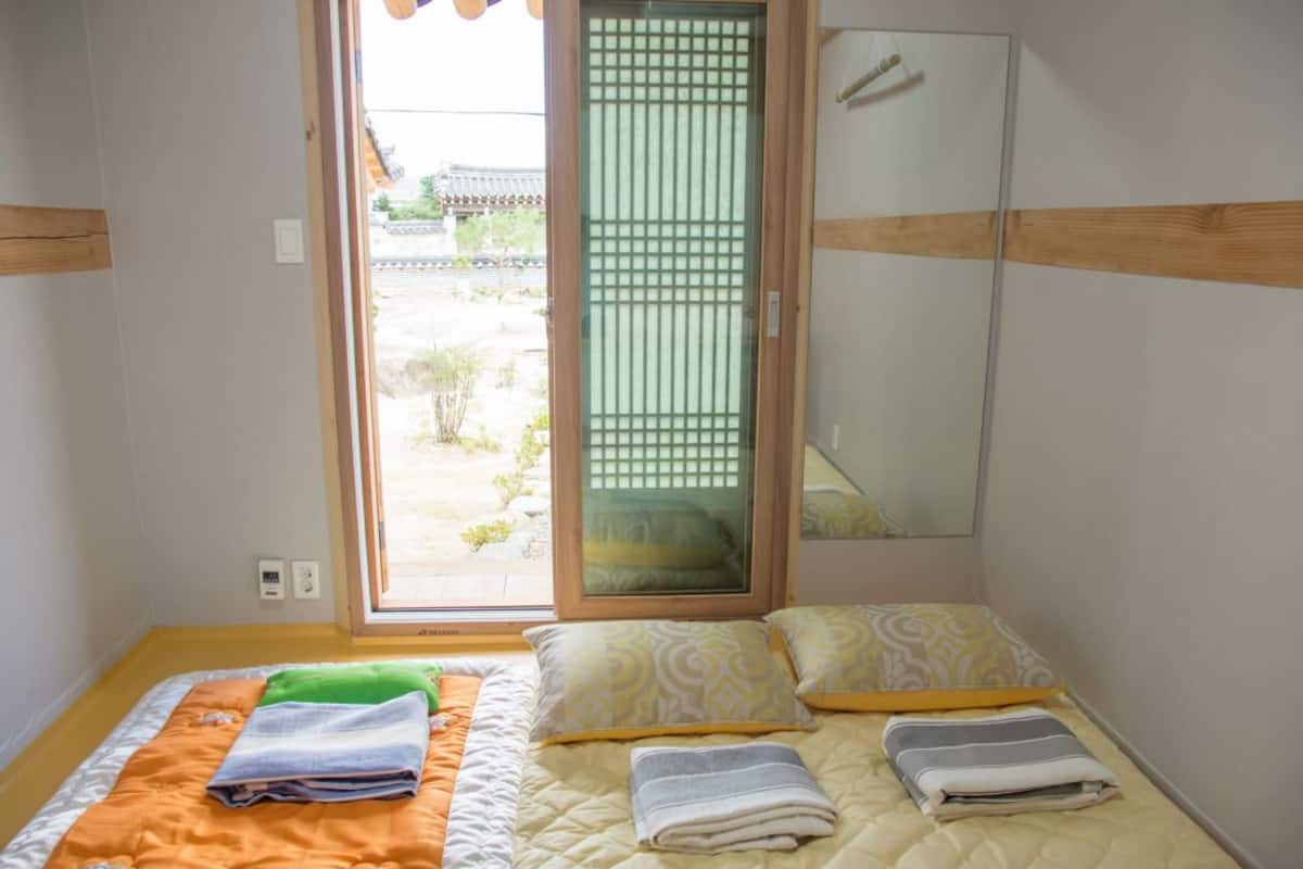 A room with a bed, a sliding door to a balcony, and a mirror on the wall.