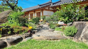 Un jardin japonais traditionnel, avec un sentier, des rochers et un bâtiment en bois doté d’un toit en tuiles.