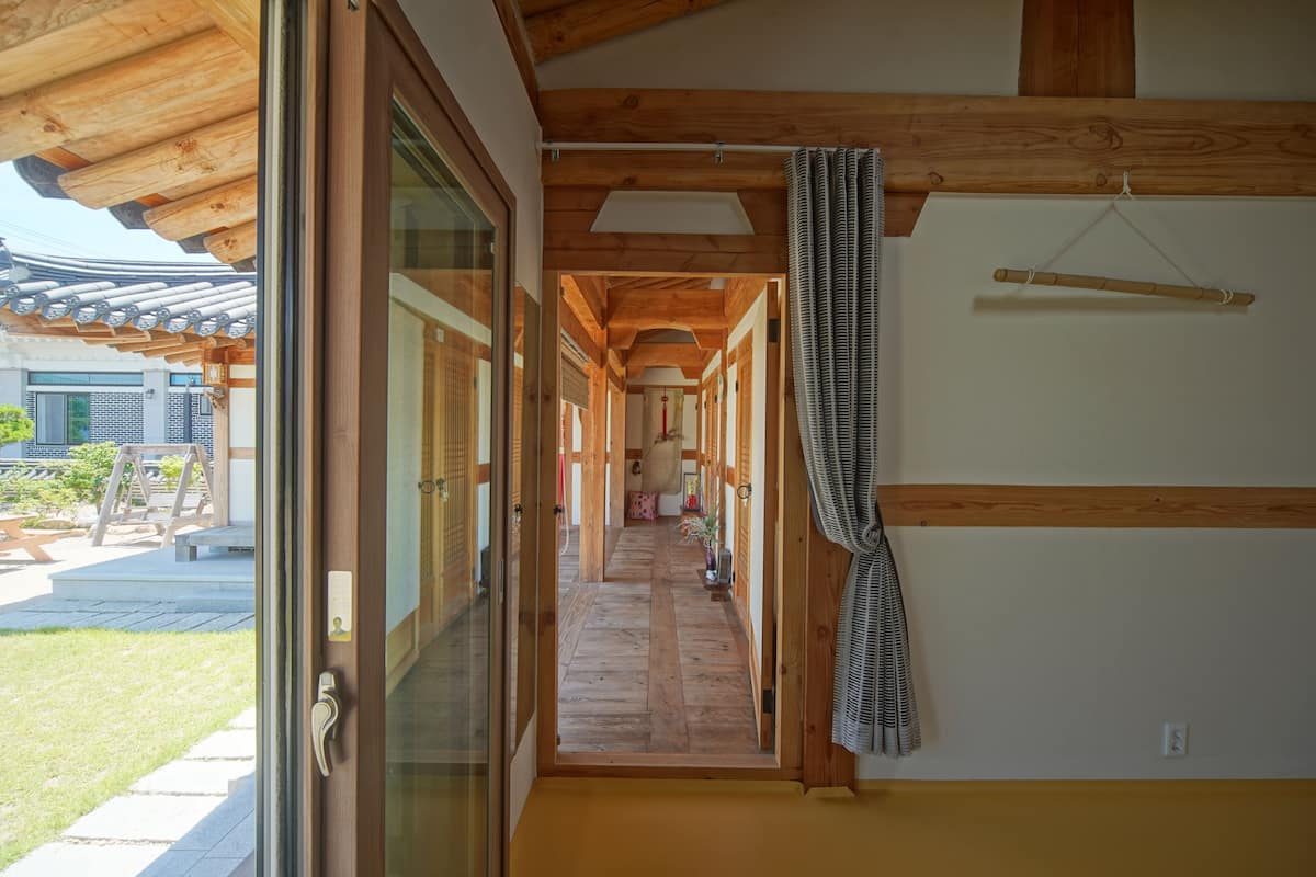 A traditional Japanese interior with wooden beams, tatami flooring, and sliding doors leading to a garden.
