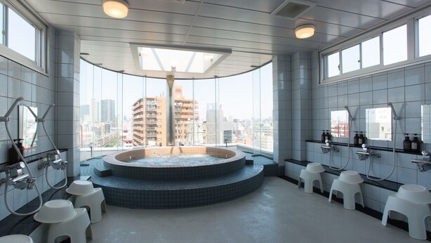 A modern bathroom with a circular hot tub, multiple sinks, and a city view.