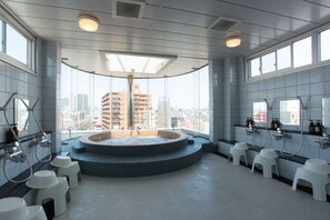 Un baño moderno con una bañera de hidromasaje circular, varios lavamanos y vistas a la ciudad.