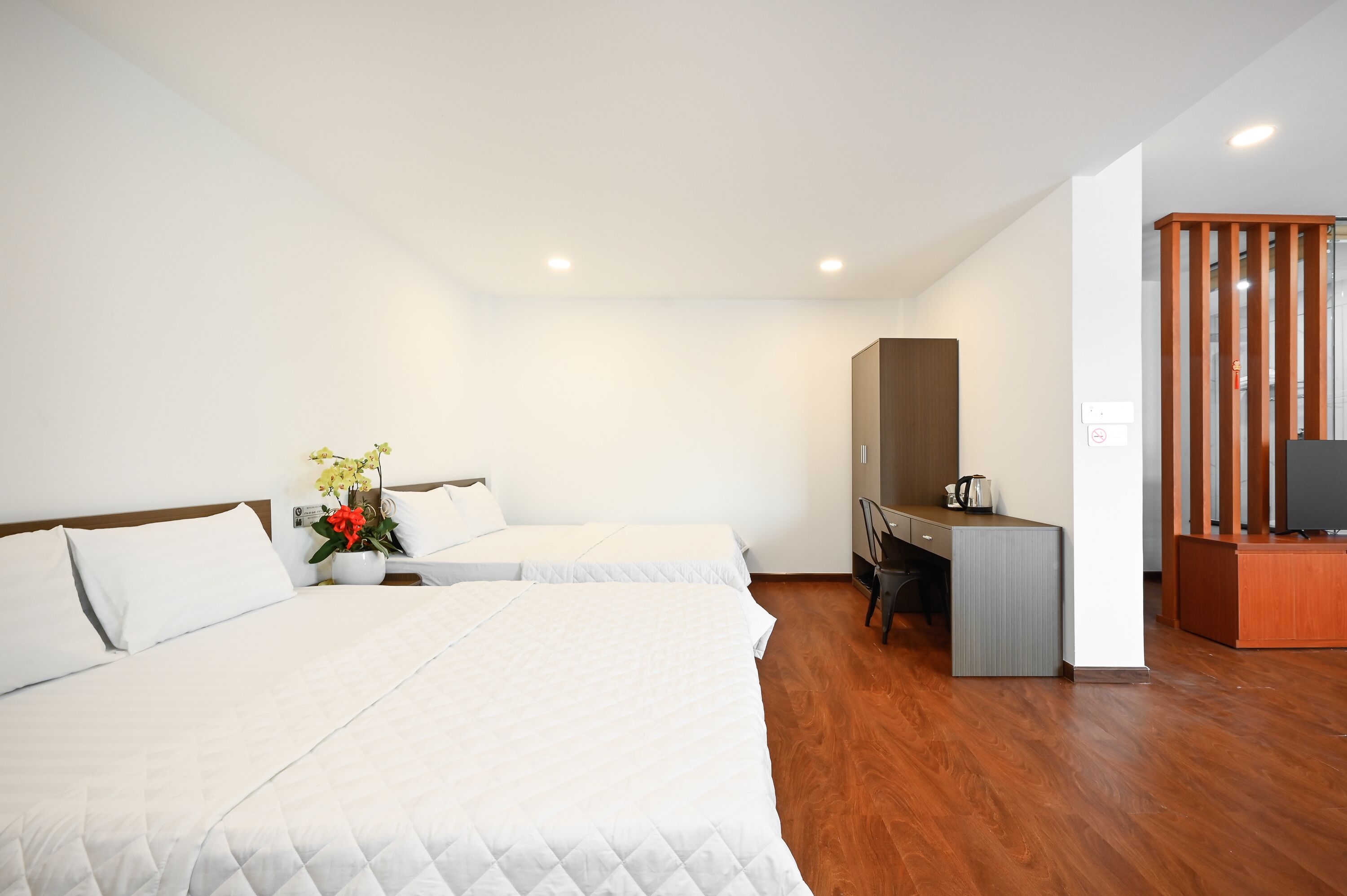 Une chambre d’hôtel avec deux lits, un bureau, une chaise, une télévision et une cloison en bois.
