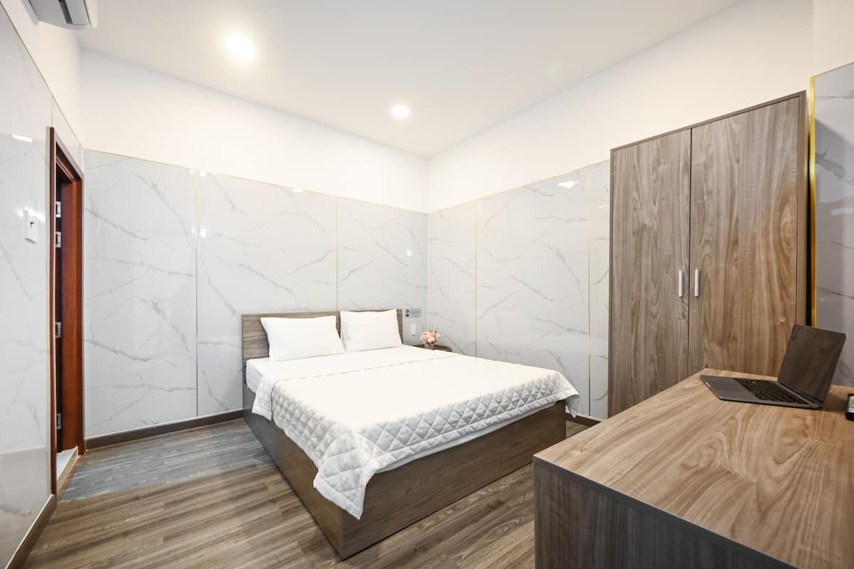 Un dormitorio moderno con cama, escritorio de madera y armario.