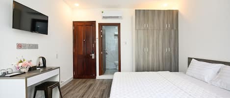 Habitación de hotel con cama, escritorio con televisor de pantalla plana, armario y zona de ducha.