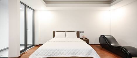 A modern bedroom with a wooden bed, a black leather chair, and a large window.