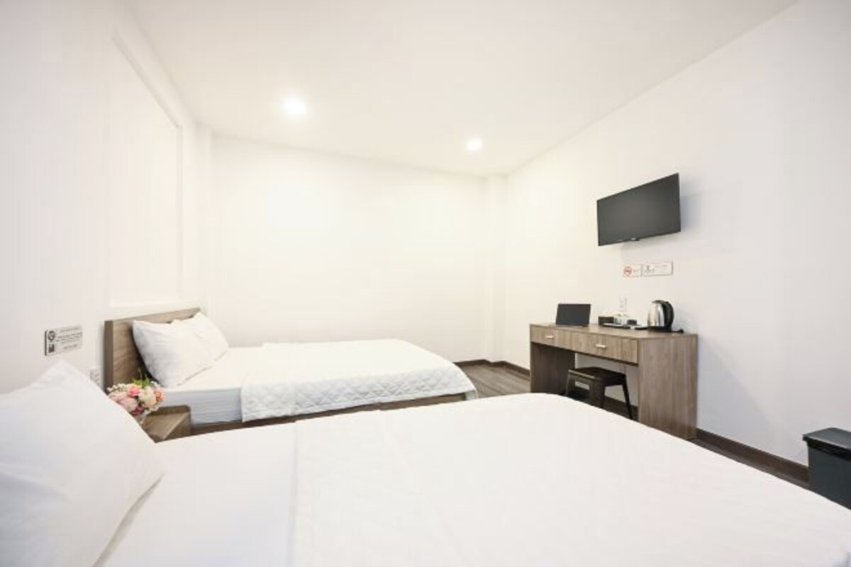 Une chambre d’hôtel avec deux lits, un bureau, un téléviseur à écran plat et une petite machine à café.