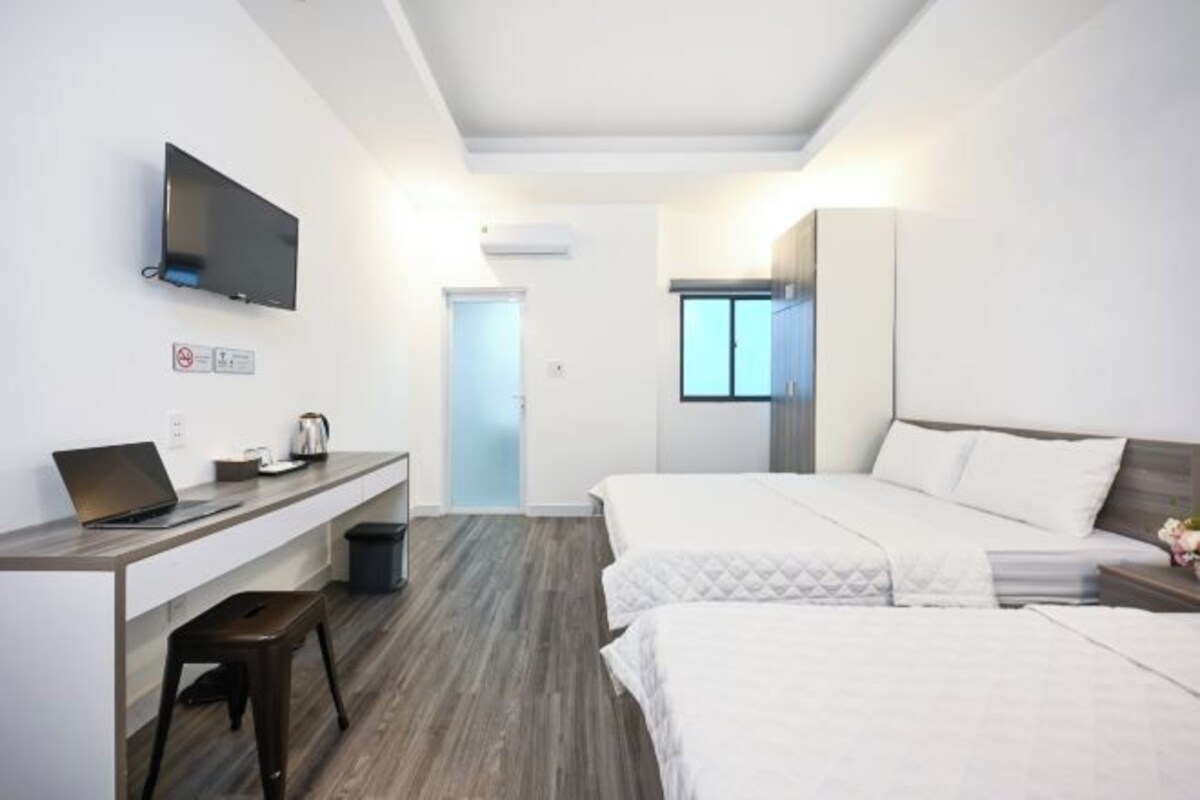 Une chambre d’hôtel moderne équipée d’un bureau, d’un ordinateur portable et d’un téléviseur à écran plat.