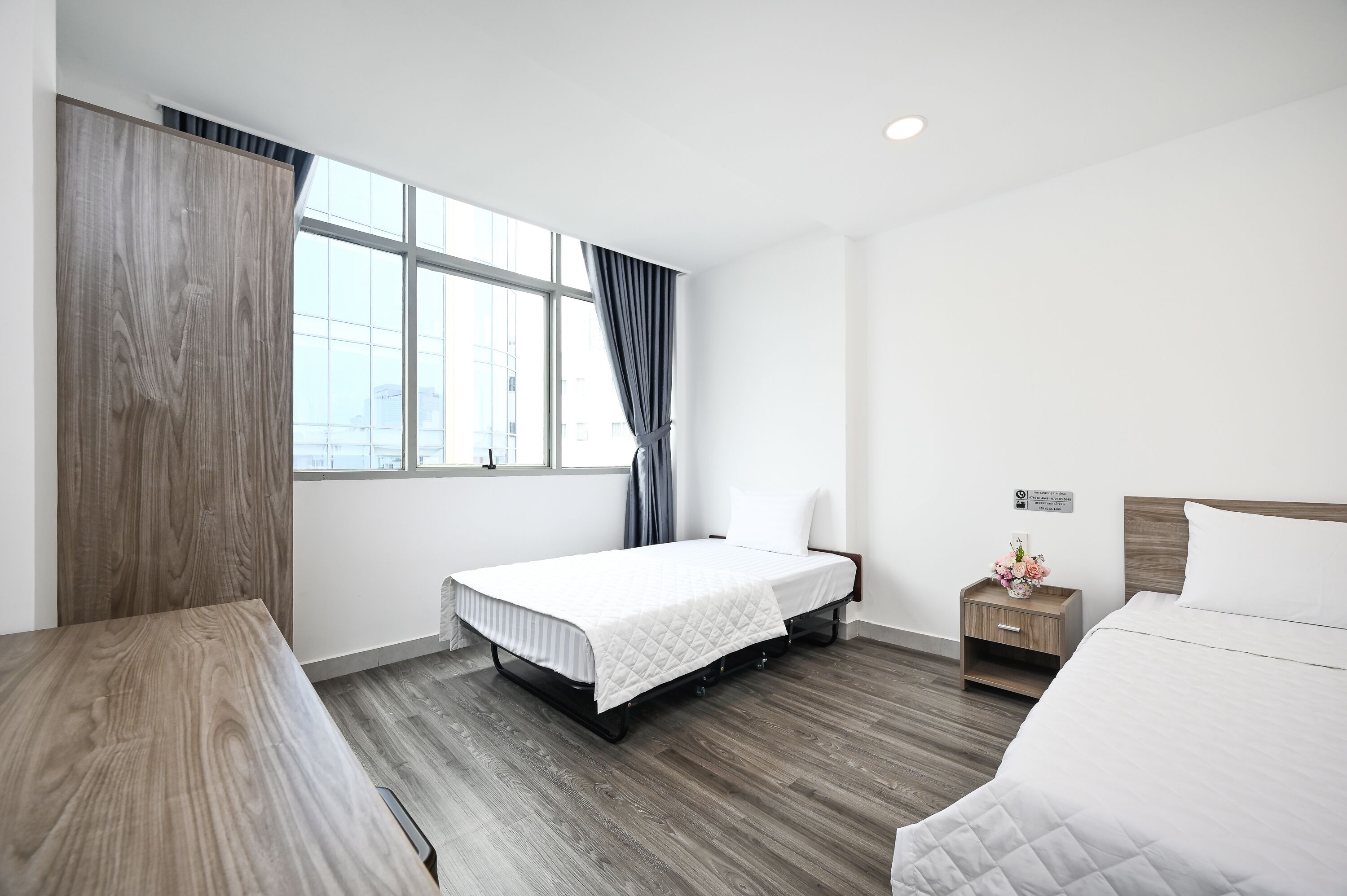 Ein modernes Hotelzimmer mit Bett, Nachttisch und einem fenster mit Vorhängen.