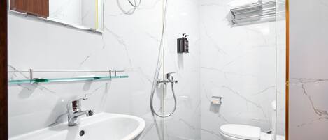 A modern bathroom with a white marble sink, a glass shelf, a shower with a handheld showerhead, and a toilet.