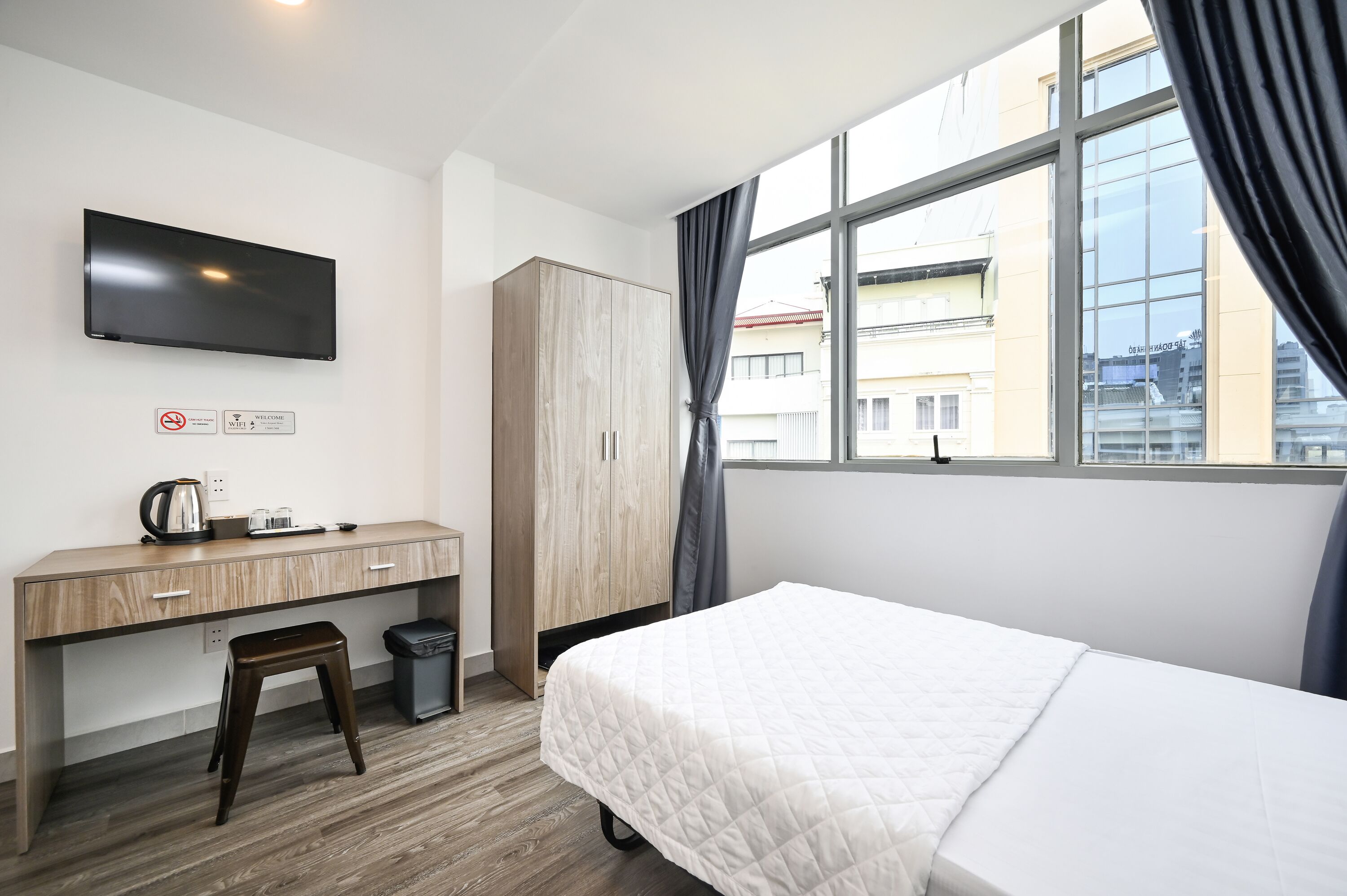 A hotel room with a bed, a desk, a TV, and a window with curtains.