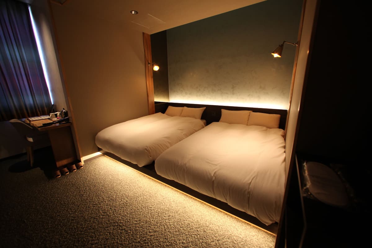 Une chambre d’hôtel avec deux lits, un bureau et une chaise.