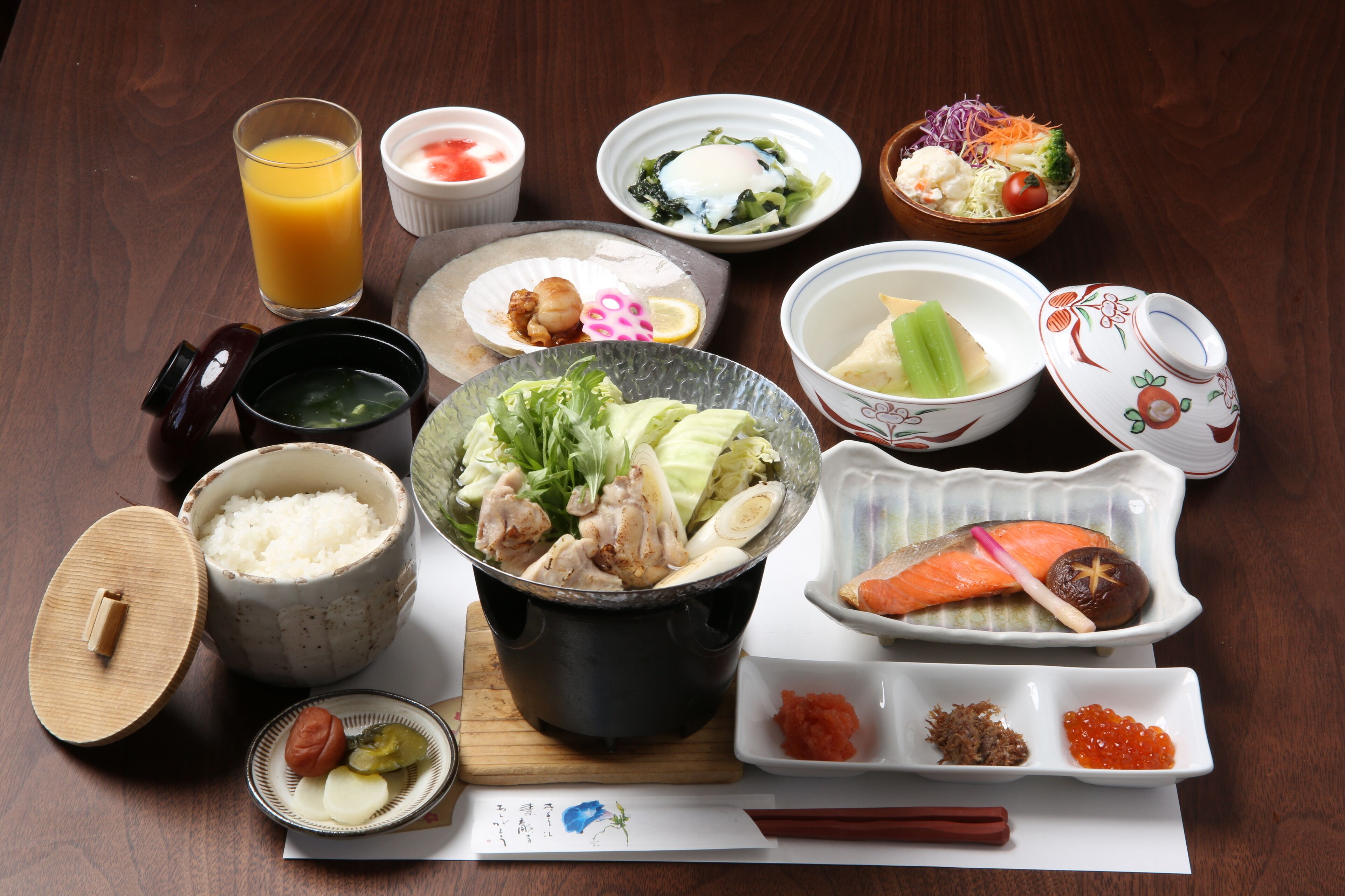 A variety of Japanese dishes including sushi, sashimi, and rice bowls, arranged on a wooden table.