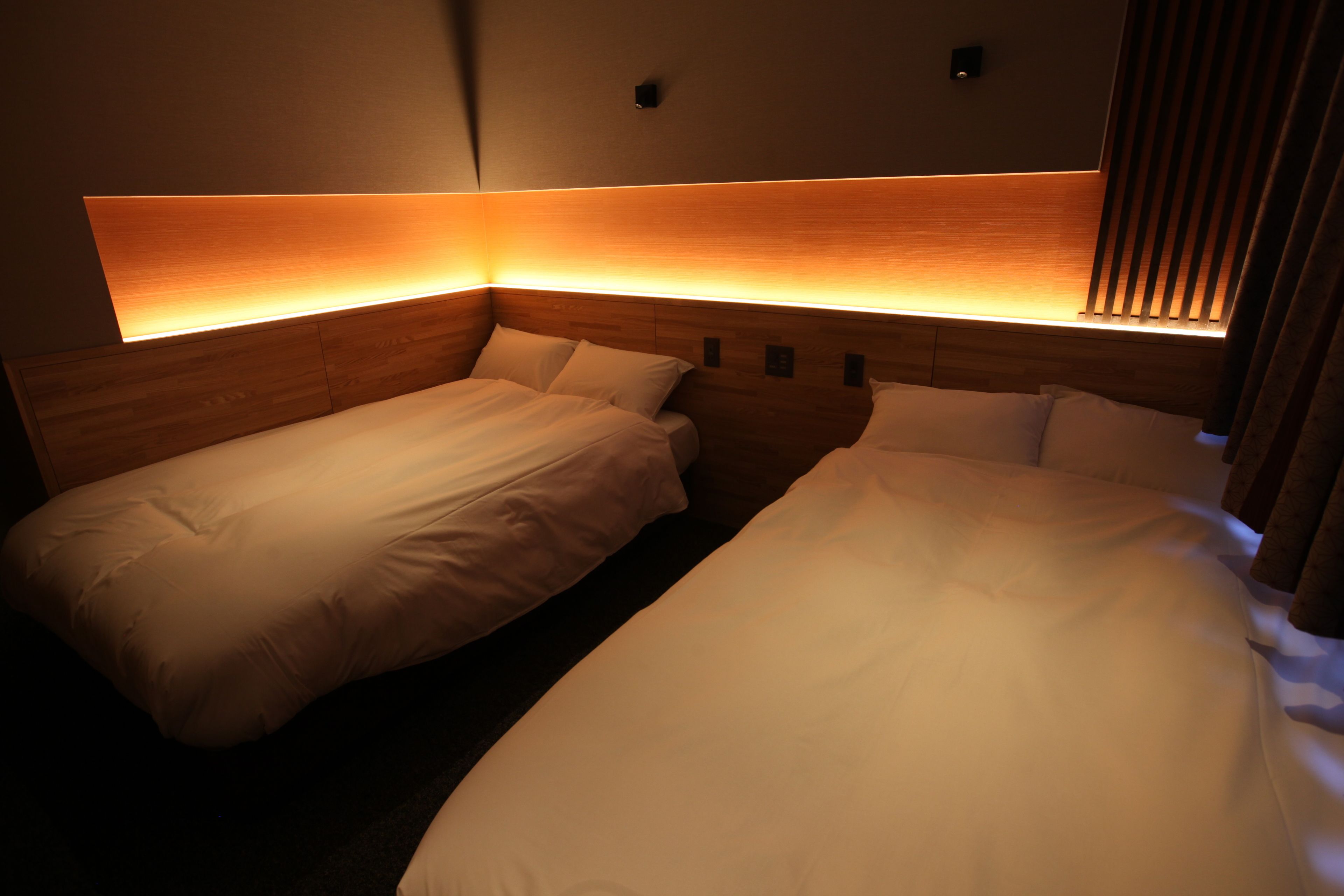 A hotel room with a large bed, a smaller bed, and a nightstand with a lamp.