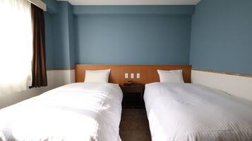 Quarto de hotel com duas camas, cabeceira de madeira, mesa de cabeceira e janela com cortinas.