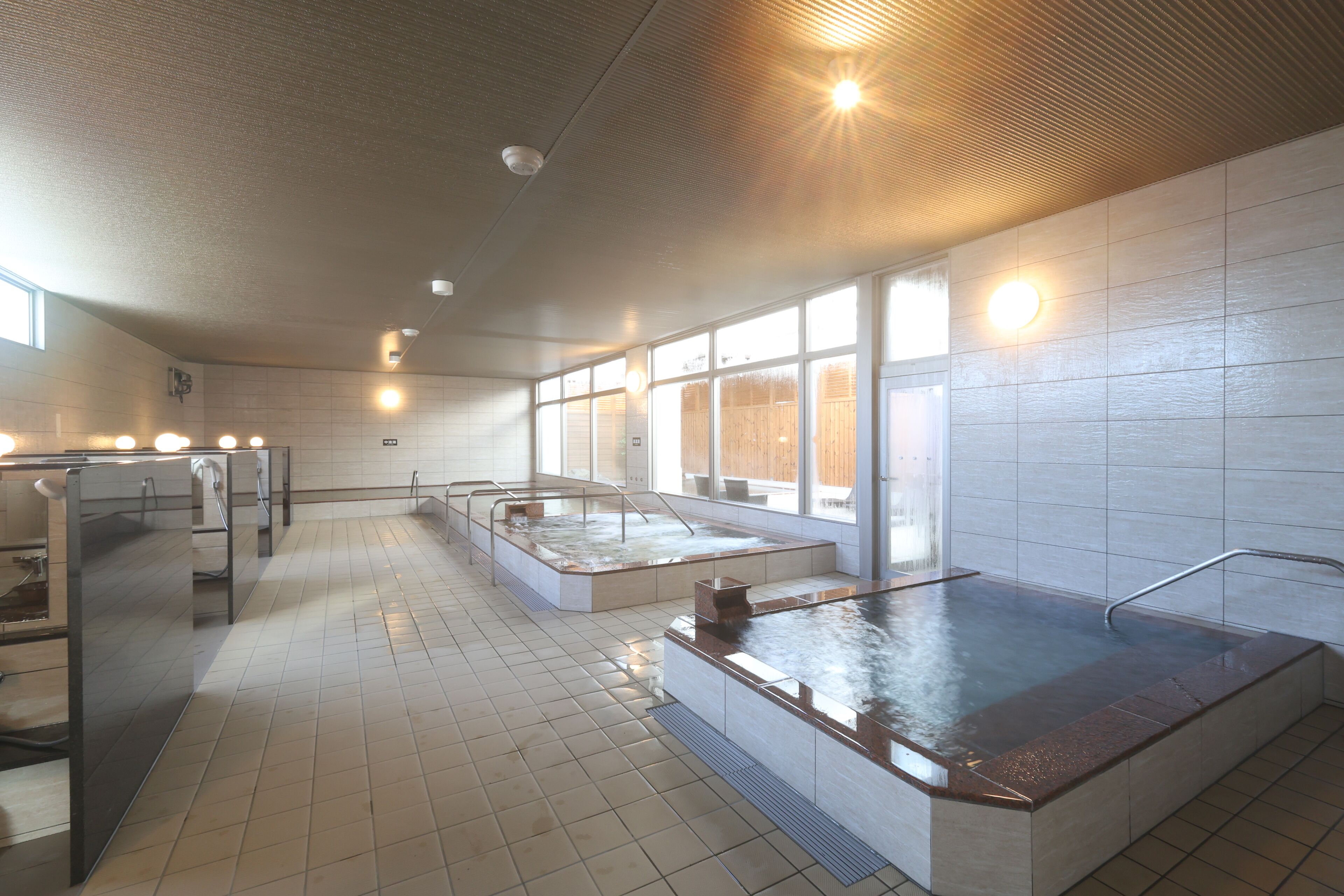 A modern spa with a large hot tub, a sauna, and a steam room.