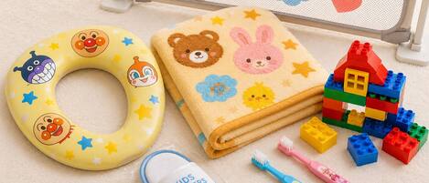 A baby gate with a bear design, a yellow ring float, a plush toy, a blanket with animal prints, and a set of building blocks.