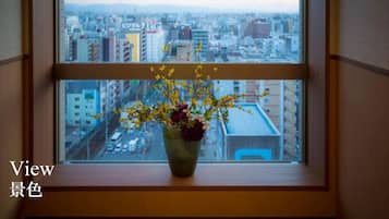 A window with a view of a cityscape, a vase with flowers, and the text "View" and "景色".