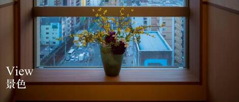 A window with a view of a cityscape, a vase with flowers, and the text "View" and "景色".