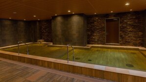 A spa area with two hot tubs, wooden flooring, stone walls, and a wooden door. - Hot Spring OSAKA HINODE HOTEL NIPPONBASHI (Osaka)