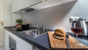 A modern kitchen with a sink, a cutting board with bread and a knife, and a glass of red wine. - Italianway   - Argonne (Milan)