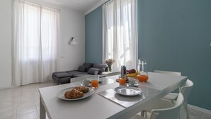 A modern dining area with a white table set for breakfast, including croissants and orange juice. - Italianway   - Argonne (Milan)