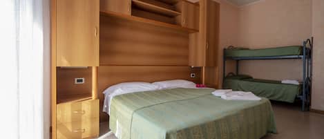 A room with a single bed, a bunk bed, wooden cabinets, and a small drawer unit.