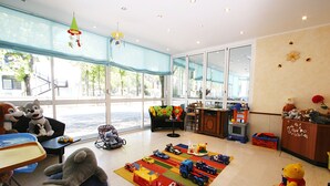 A spacious room with large windows, a play area with toys, and a seating area with plush toys. - Hotel Nuova Flavia (Lignano Sabbiadoro)