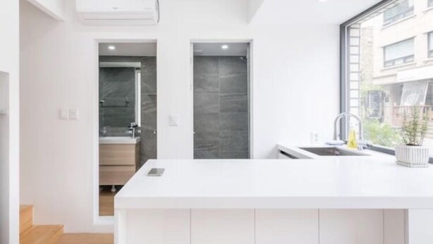 A modern kitchen with a white countertop, a sink, and a window. - The Stay Simple (Seoul)