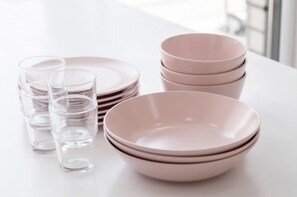 A stack of pink plates and clear glasses on a white table. - The Stay Simple (Seoul)