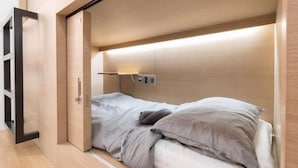 A compact room with a bed, a small bedside table, and a wall-mounted light fixture. - The Stay Simple (Seoul)