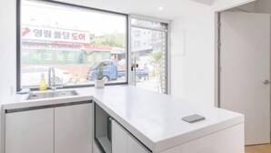 A modern kitchen with a large window, a sink, and a countertop. - The Stay Simple (Seoul)