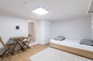 A small, modern room with a bed, a foldable desk, and a chair. - The Stay Simple (Seoul)