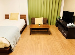 Une chambre d’hôtel comprenant un lit, un canapé, une table basse, une télévision et une commode.