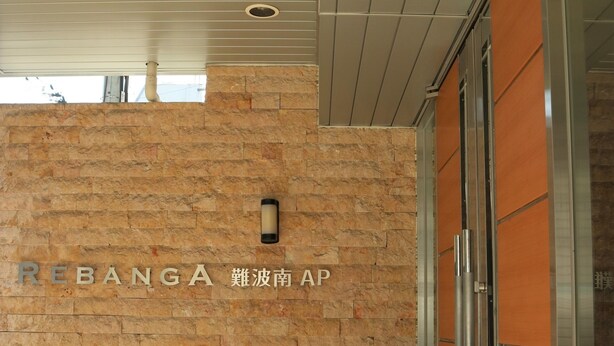 A building entrance with a stone wall and a sign that reads "REBANGA". - At RLiS House Namba Minami (Osaka)