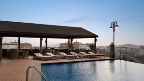 A rooftop pool area with lounge chairs and a covered seating area, overlooking a cityscape. - Ramada Plaza by Wyndham Chennai (Chennai)