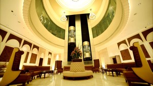 A spacious lobby with a central seating area, a high ceiling with a circular skylight, and modern chandeliers. - Ramada Plaza by Wyndham Chennai (Chennai)