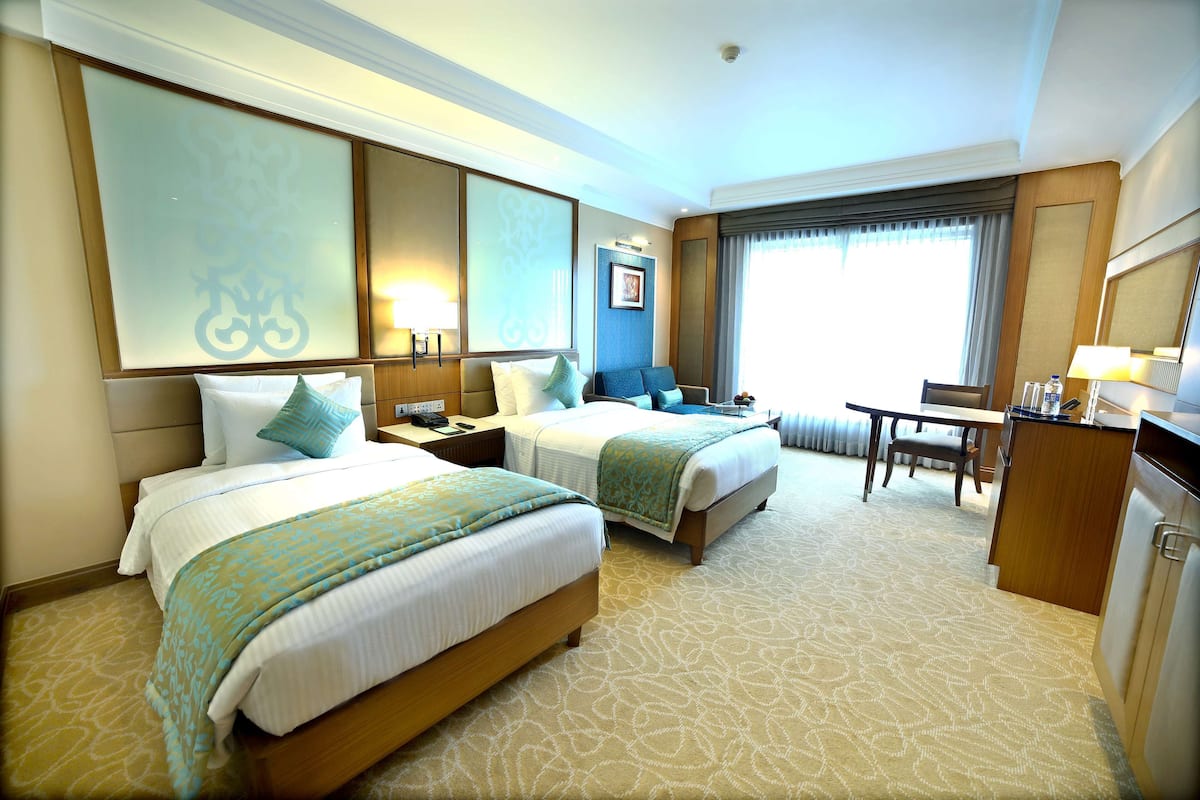 Une chambre d’hôtel avec deux lits, un bureau et une chaise.
