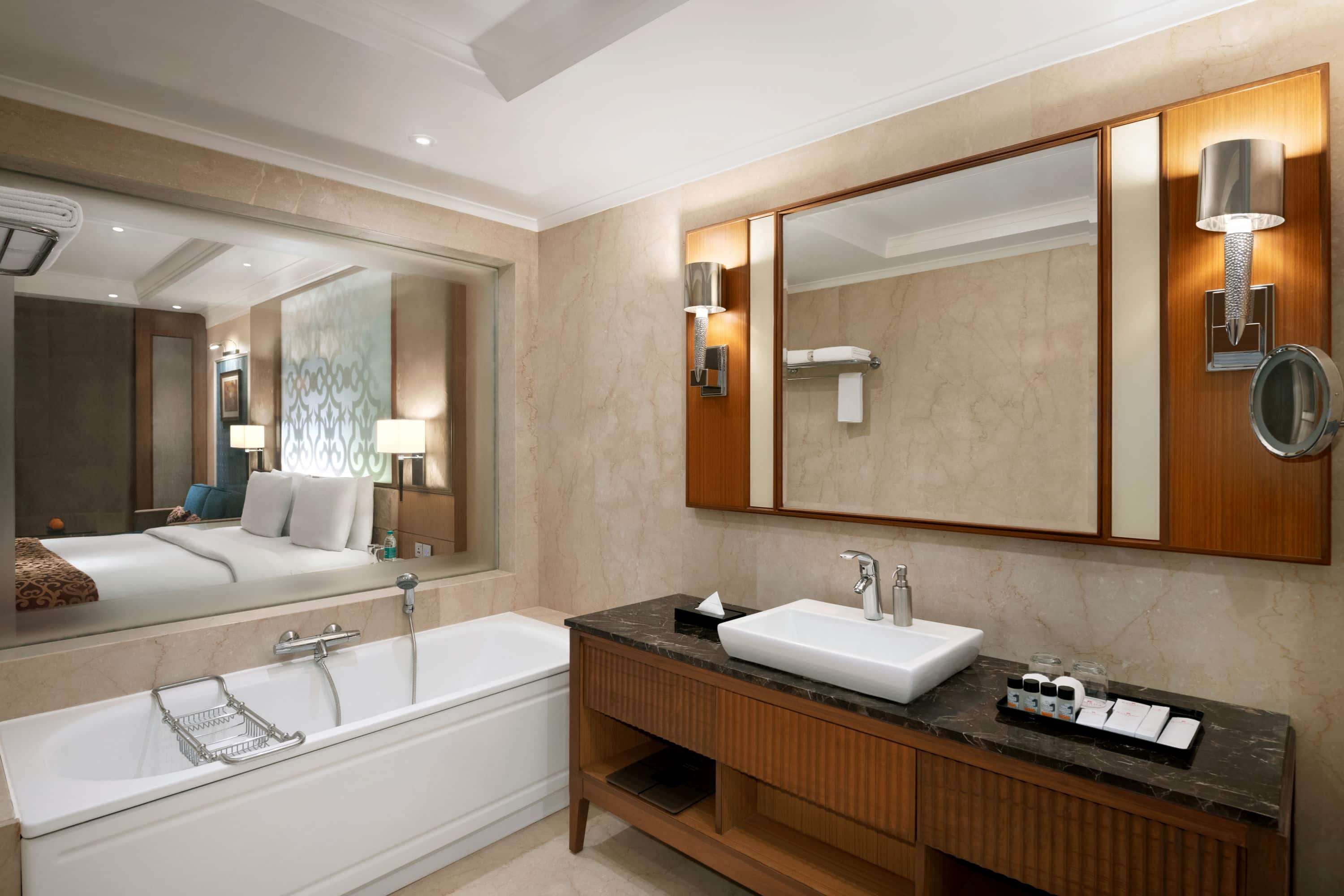 A modern bathroom with a large mirror, a bathtub, a sink, and a vanity.