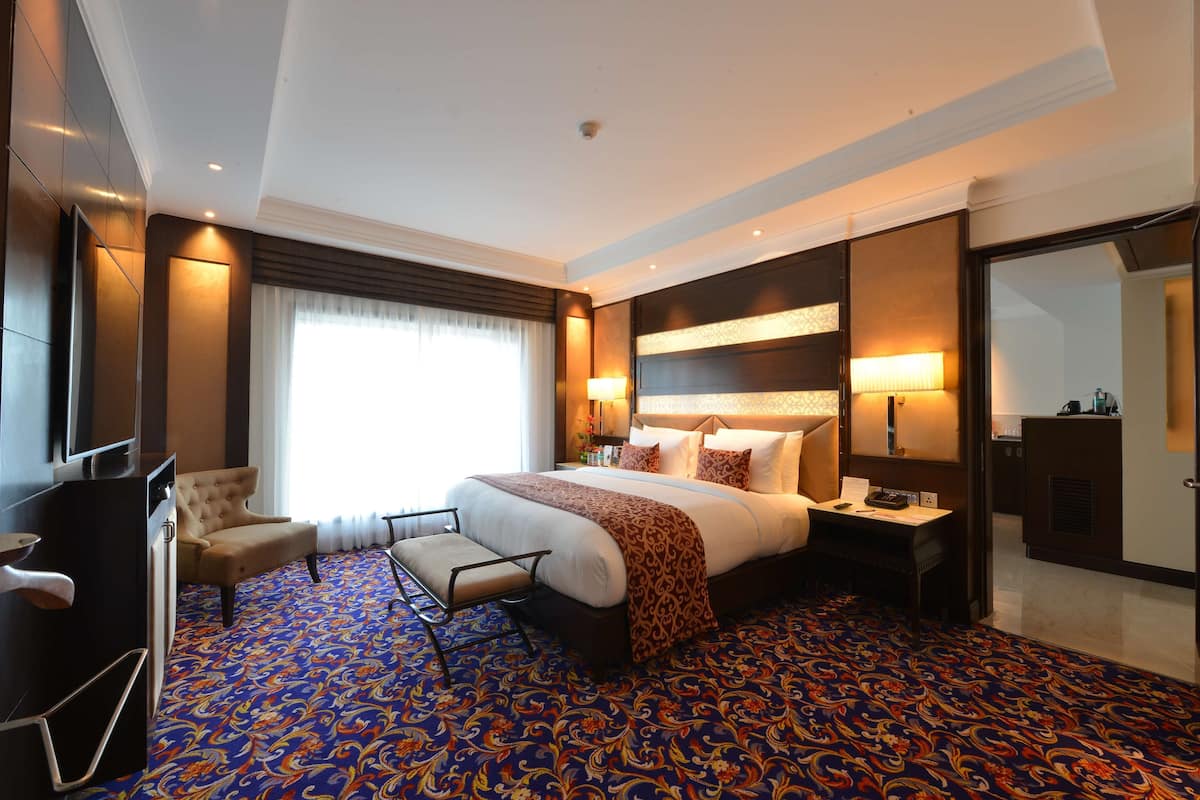 Une chambre d’hôtel avec un grand lit, un bureau, une chaise et un téléviseur.