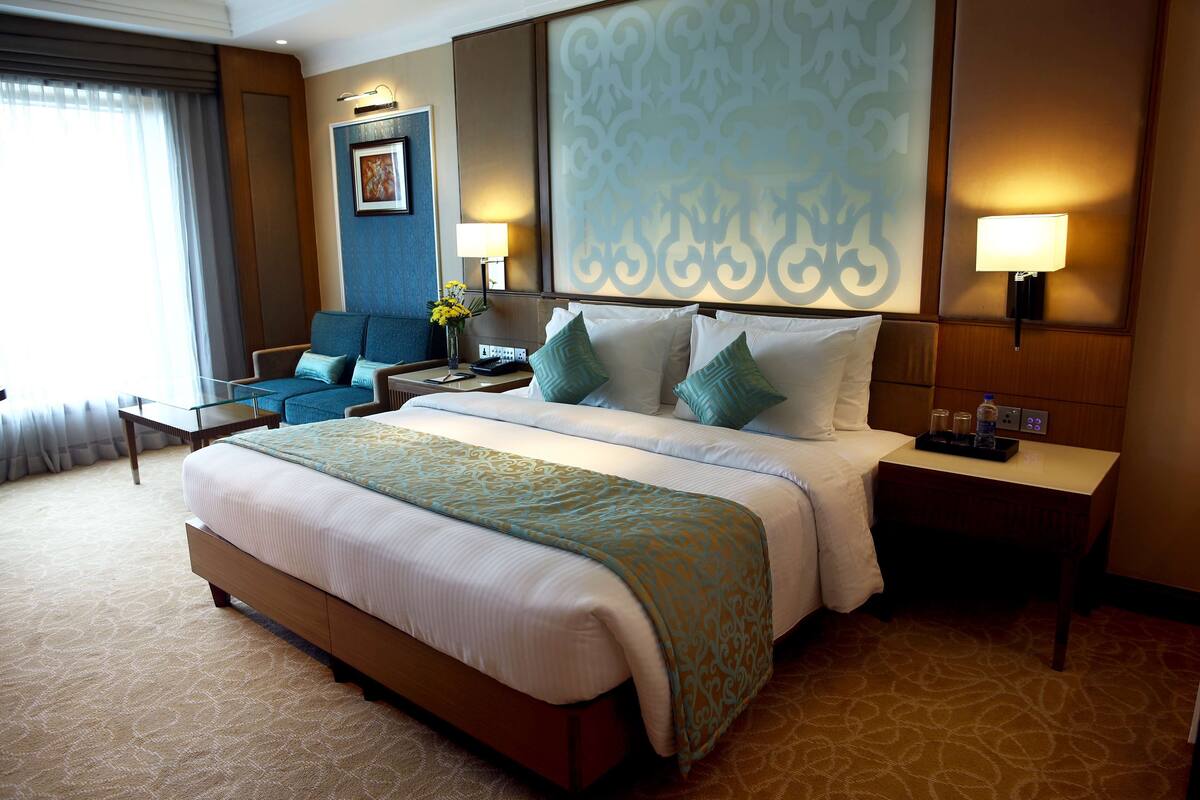 Une chambre d’hôtel avec un grand lit, un bureau, une chaise et un mur orné de panneaux décoratifs.