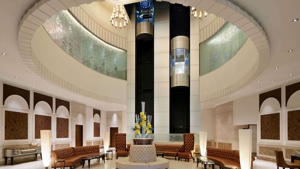 A spacious lobby with a central round seating area, a high ceiling with a circular design, and a modern elevator. - Ramada Plaza by Wyndham Chennai (Chennai)