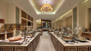 A buffet setup with multiple food stations and a central seating area. - Ramada Plaza by Wyndham Chennai (Chennai)