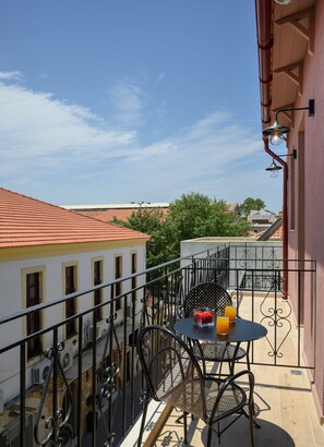 En balkon med et bord og stole, et glas appelsinjuice og en skål med jordbær.