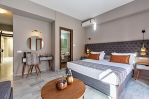 Et moderne hotelværelse med en stor seng, et rundt bord med dekorative genstande, et rundt spejl, et toiletbord med spejl og en aircondition.